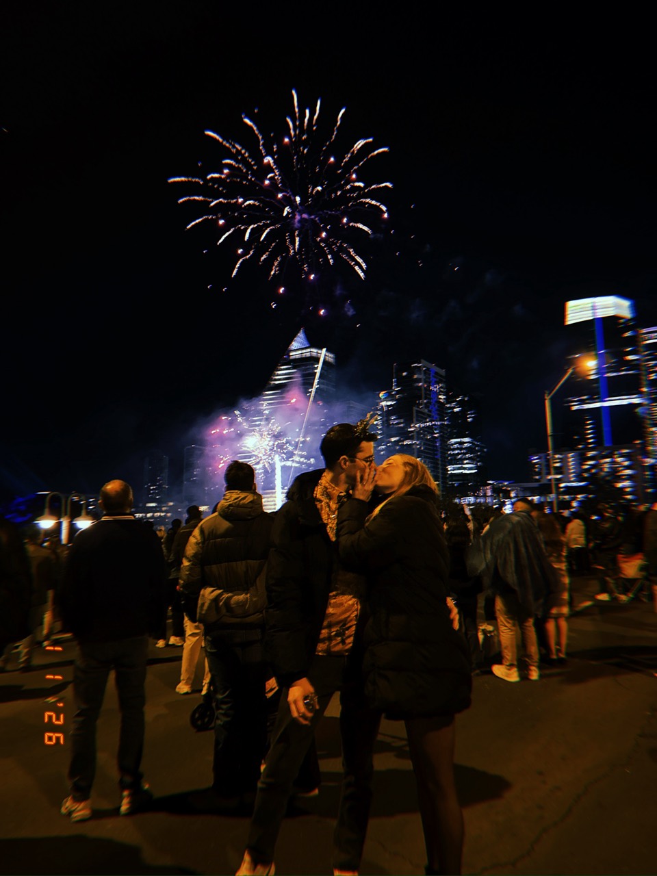 Tyler and Lauren kissing beneath fireworks over the Austin skyline